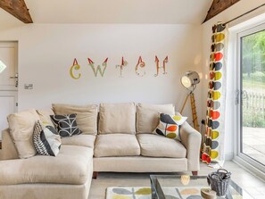 A living room with a sofa, pillows, a lamp, and a wall with letters.