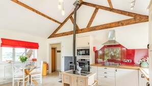 A kitchen with a wood beam ceiling, a stove, and a red backsplash.