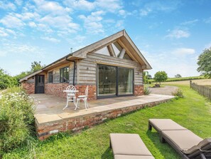 A wooden house with a patio, a sliding glass door, and a brick wall. - 1 bedroom accommodation in Aberhafesp, near Newtown (Newtown)