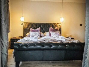 A bed with a tufted headboard, two bedside tables, and a nightstand. - 1 bedroom accommodation in Aberhafesp, near Newtown (Newtown)