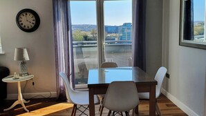 Ein Essbereich mit Tisch, Stühlen, einer Lampe, einer Uhr und Blick ins Freie.