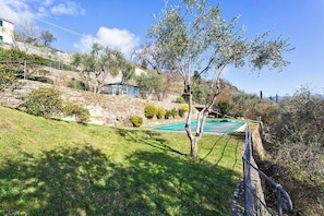 Ein Wohnhaus mit Swimmingpool, Steinmauern und Blick auf eine Hügellandschaft.