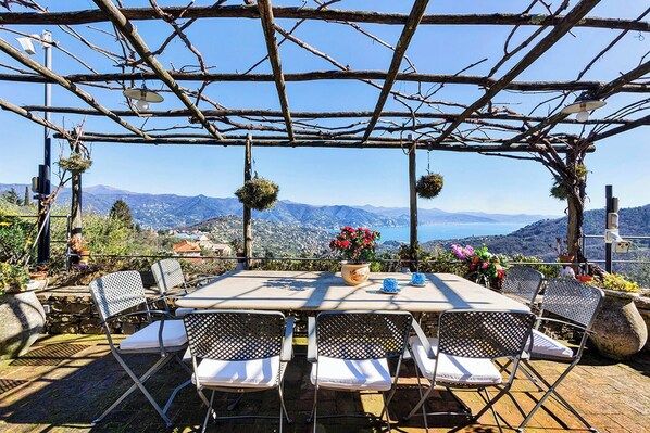 Eine Terrasse mit einer Pergola, Sitzgelegenheiten im Freien und Blick auf die Berge.