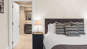 Ein Schlafzimmer mit einem Bett, Nachttisch, Lampe und Kissen mit Muster.