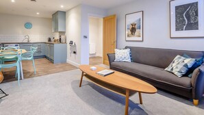 Ein modernes Wohnzimmer mit einer Couch, einem Couchtisch und einem Essbereich mit Stühlen.