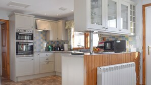A kitchen with white cabinets, a built-in oven, a microwave, a kettle, and a fruit bowl on the counter. - Castle Peroch-UK5698 (By Dunkeld, Pitlochry)
