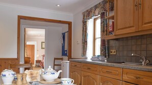 Een keuken met houten kastjes, een spoelbak en een eettafel gedekt met theekopjes en borden.