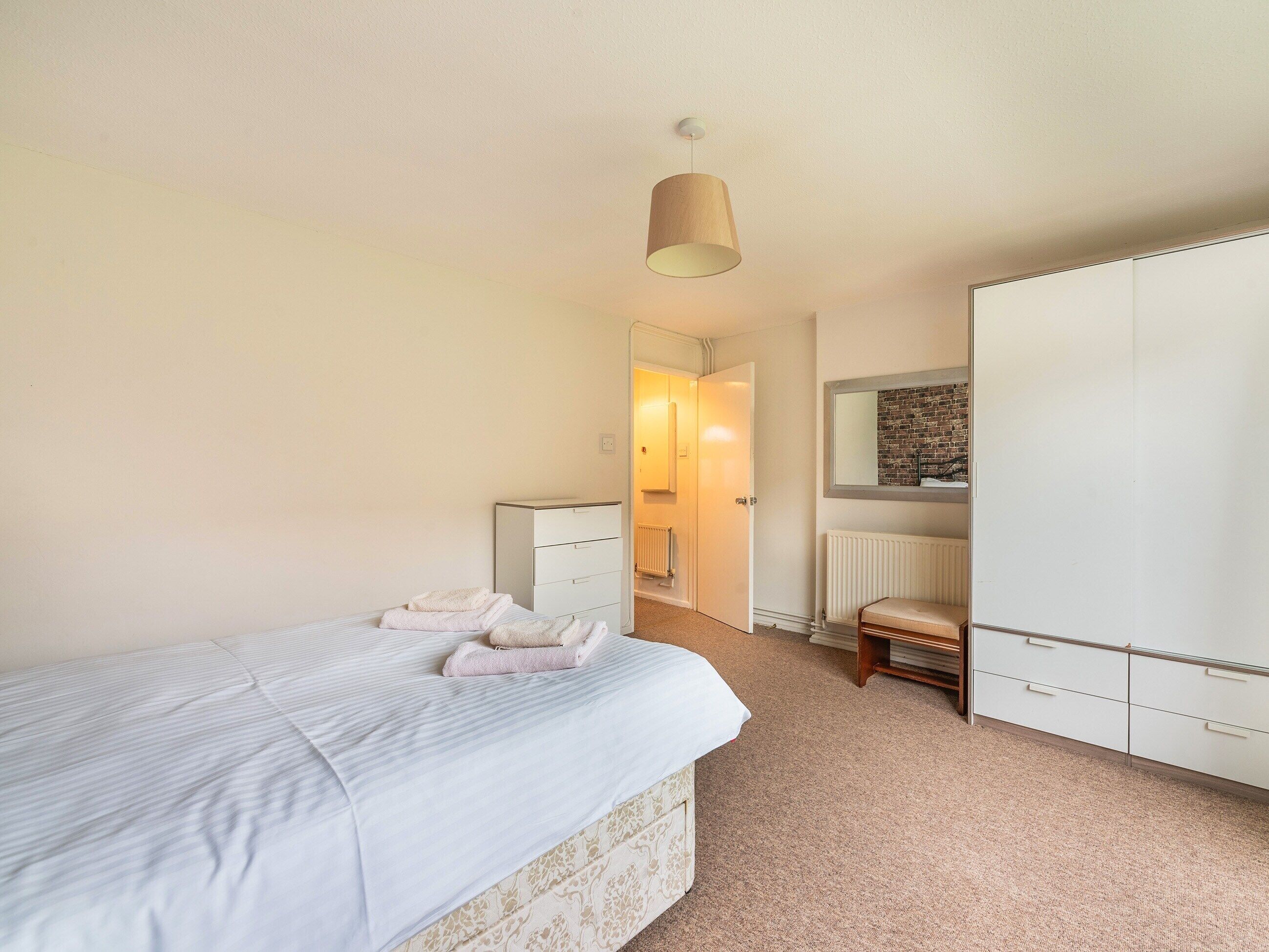 A bedroom with a bed, a dresser, a chair, and a radiator.