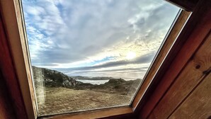 A skylight with a view of a cloudy sky and distant land. - Orchid Cottage - UK5866 (Clachtoll, near Lochinver)