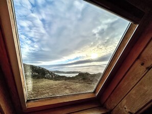 Um claraboia com vista para um céu nublado e terras distantes.