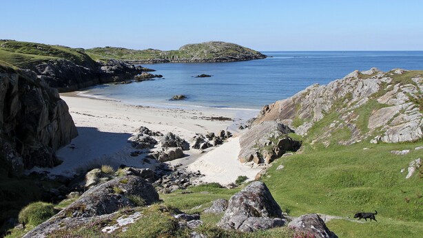 A coastal landscape with a beach, rocky terrain, and a small island in the distance. - Orchid Cottage - UK5866 (Clachtoll, near Lochinver)