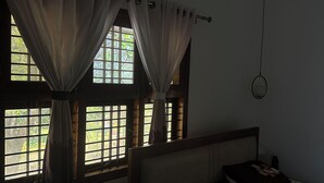 A dimly lit room with a bed, curtains, and a window with a view of greenery outside. - Perfect 1-bedroom bed & breakfast with AC in Bengaluru (Bengaluru)