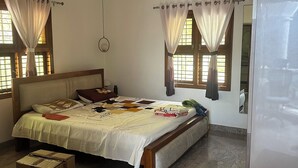 A bedroom with a bed, a ceiling fan, an air conditioner, and a window with curtains. - Perfect 1-bedroom bed & breakfast with AC in Bengaluru (Bengaluru)