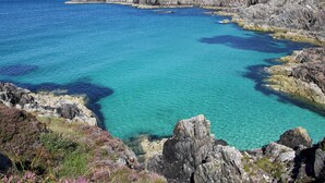A coastal landscape with rocky terrain and clear blue waters.