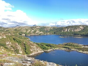 A mountainous landscape with a large body of water surrounded by rocky terrain and greenery.