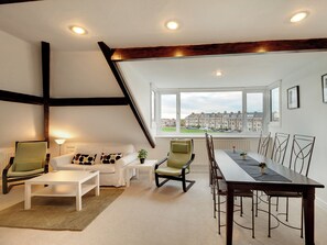 Ein modernes Wohnzimmer mit Essbereich, großen Fenstern und Blick auf Wohnhäuser.