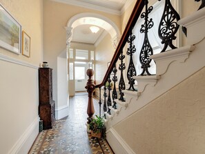 Eine prachtvolle Treppe mit aufwendigen schwarzen Geländern, einem gemusterten Fliesenboden und einer weißen Wand mit einem gerahmten Bild.