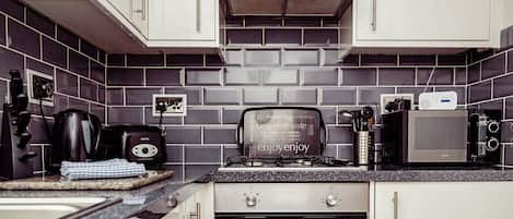 A kitchen with white cabinets, a black countertop, a toaster, a kettle, and a microwave.