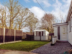 A residential area with a wooden fence, a small shed, and a house with a white door. - 3 bedroom accommodation in Flookburgh (Flookburgh)