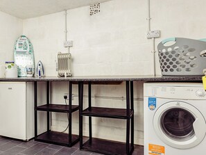 Un espace dédié à la lessive, équipé d’un lave-linge, d’un fer à repasser et d’une planche à repasser.