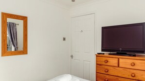 Ett hotellrum med en säng, en byrå i trä med ett tv-apparats och en spegel på väggen.