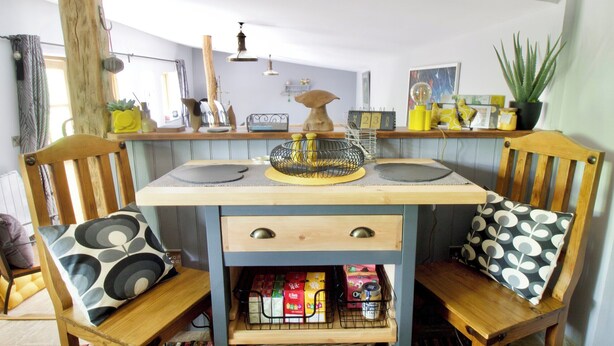 Une cuisine avec des chaises en bois, un îlot central et divers ustensiles de cuisine.