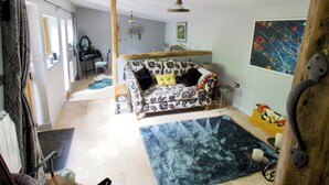 Un salon chaleureux avec un canapé à motifs, un tapis bleu et un plafond avec une poutre en bois.
