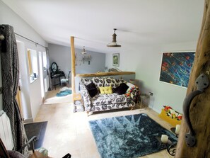Ein gemütliches Wohnzimmer mit einer gemusterten Couch, einem blauen Teppich und einer Holzbalkendecke.