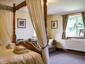 Une chambre à coucher avec un lit à baldaquin, un coin salon avec un canapé et une fenêtre avec des rideaux.