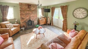 Una sala de estar con chimenea de ladrillo, sofás de cuero, una mesa de centro y un reloj en la pared.