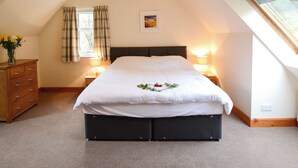 Een slaapkamer met een bed, een kaptafel, een raam met gordijnen, een bedlamp en een schilderij aan de muur.