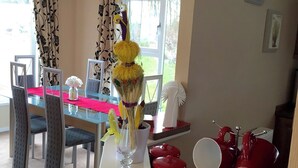 Un coin repas avec une table en verre, des chaises et un vase contenant un objet décoratif.