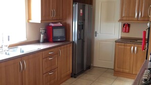 Une cuisine avec des meubles de rangement en bois, un réfrigérateur en acier inoxydable, un four à micro-ondes et une cuisinière à gaz.