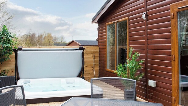 Une terrasse avec un jacuzzi, une table et des chaises.