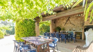 An outdoor patio with a stone wall, wooden table, and chairs.