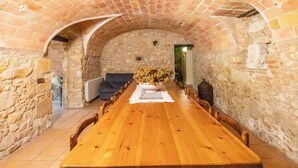 A long wooden table in a stone-walled room with an arched ceiling.
