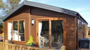 Eine Holzhütte mit Veranda, großen Fenstern und einer Schiebetür.