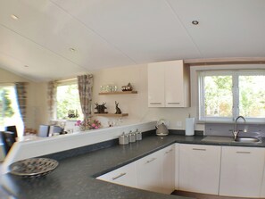 A modern kitchen with white cabinets, a black countertop, and a window with blinds. - 3 bedroom accommodation in Felton (Felton)