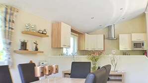 Eine moderne Küche mit Holzschränken, einem Esstisch mit Stühlen und einer Vase mit Blumen.