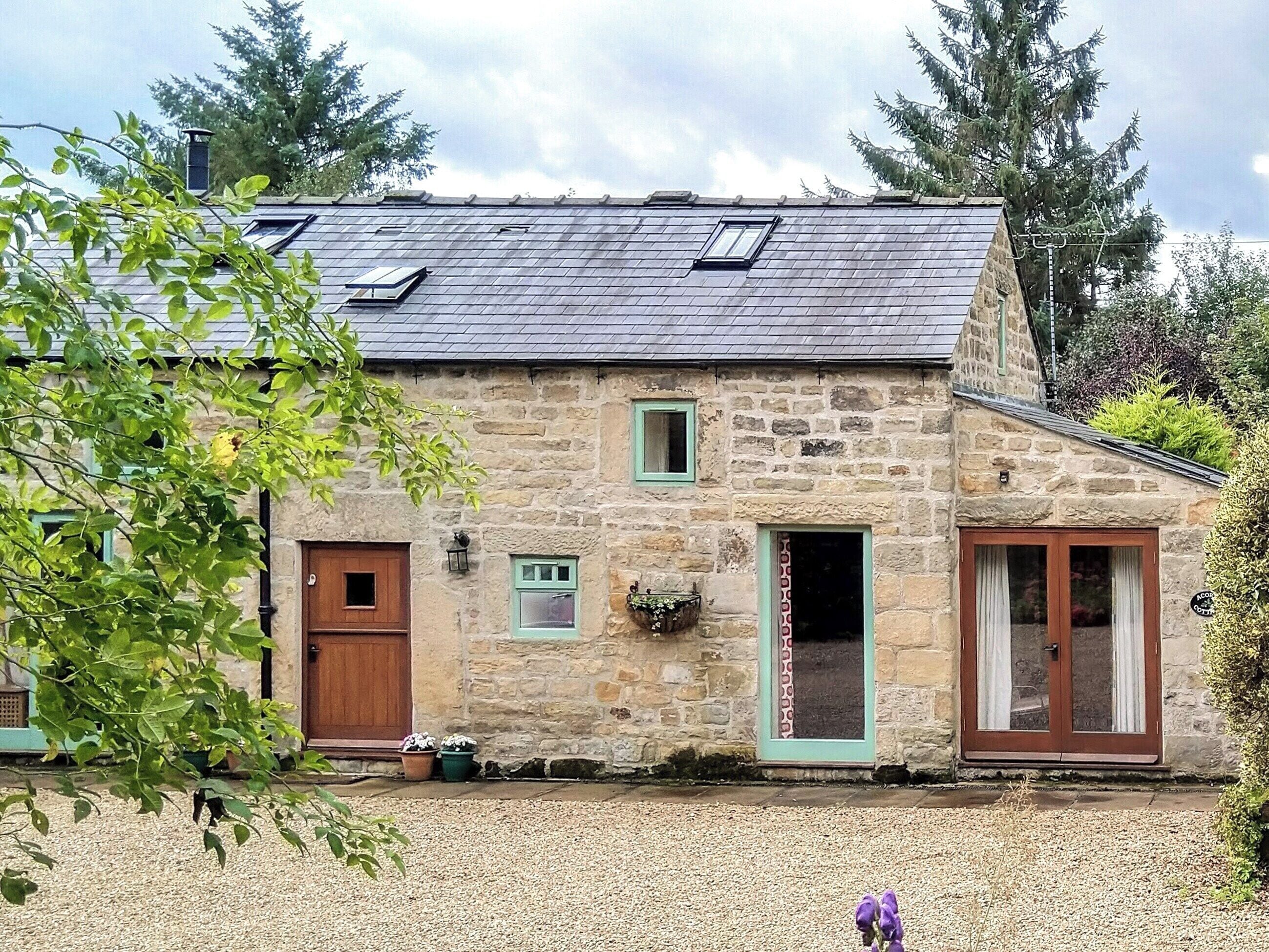 Un bâtiment en pierre avec un toit en pente, deux fenêtres et une porte.