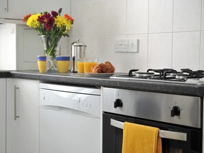 A kitchen with a dishwasher, a stove, and a yellow towel hanging on the oven door. - 1 bedroom accommodation in Cheltenham (Cheltenham)