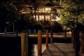 A waterfront property with a wooden dock leading to a house with a balcony.