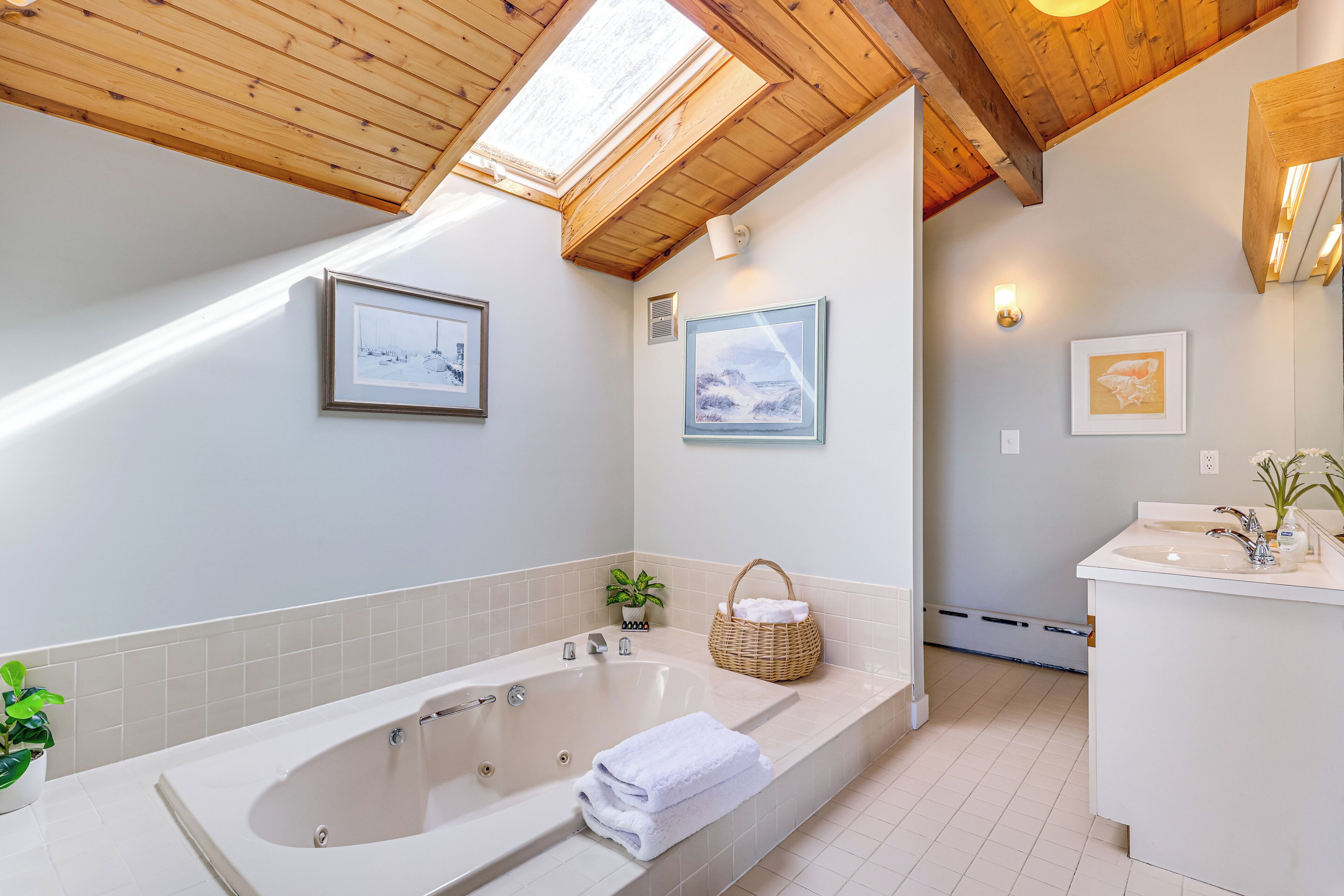 Une salle de bain moderne avec une baignoire sur pieds, un lavabo et une petite plante.