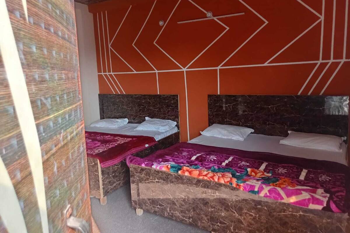 A room with two beds, each with a headboard and pillows, and a small table with a chair.