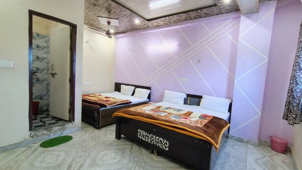 A room with two beds, a ceiling fan, and a patterned floor. - Shri Kishori Kunj Home Stay (Vrindavan)