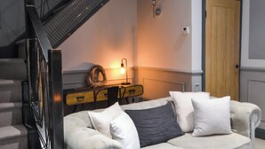A living room with a sofa, a staircase, a desk, and a door.