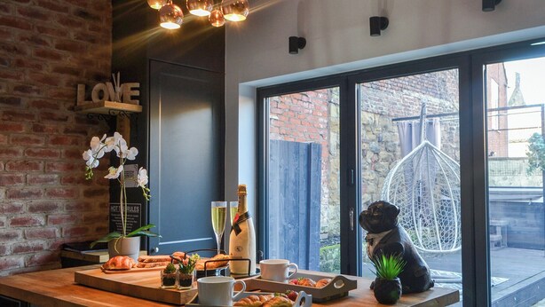 A cozy café with a brick wall, a wooden counter, and a large window offering a view of the street.
