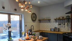 A modern kitchen with a wooden countertop, a built-in oven, and hanging pots.