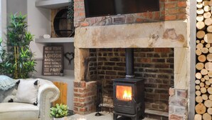 A cozy living room with a brick fireplace, a sofa, a coffee table with a candle, and a TV mounted above the fireplace.