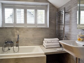 A bathroom with a bathtub, a shower, a towel stack, and a sink. - 2 bedroom accommodation in Plas Cilybebyll, near Pontardawe (Plas Cilybebyll, near Pontardawe)